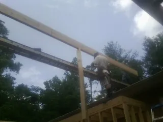 Carpenter setting a ridge beam over a new addition frame — Ice Dam Removal by Roofing Brothers in Green