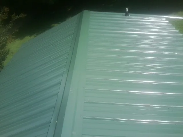 New green metal panels meeting at the ridge of a roof — Flat Roof Repair work by our crew in Green