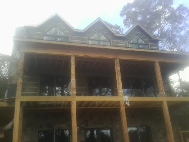 Dormers and porch framing on a large log home under construction — Roof Coating work by our crew in Green