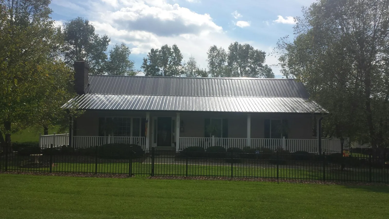 Gray metal roof on a brick ranch with a full width front porch in Green