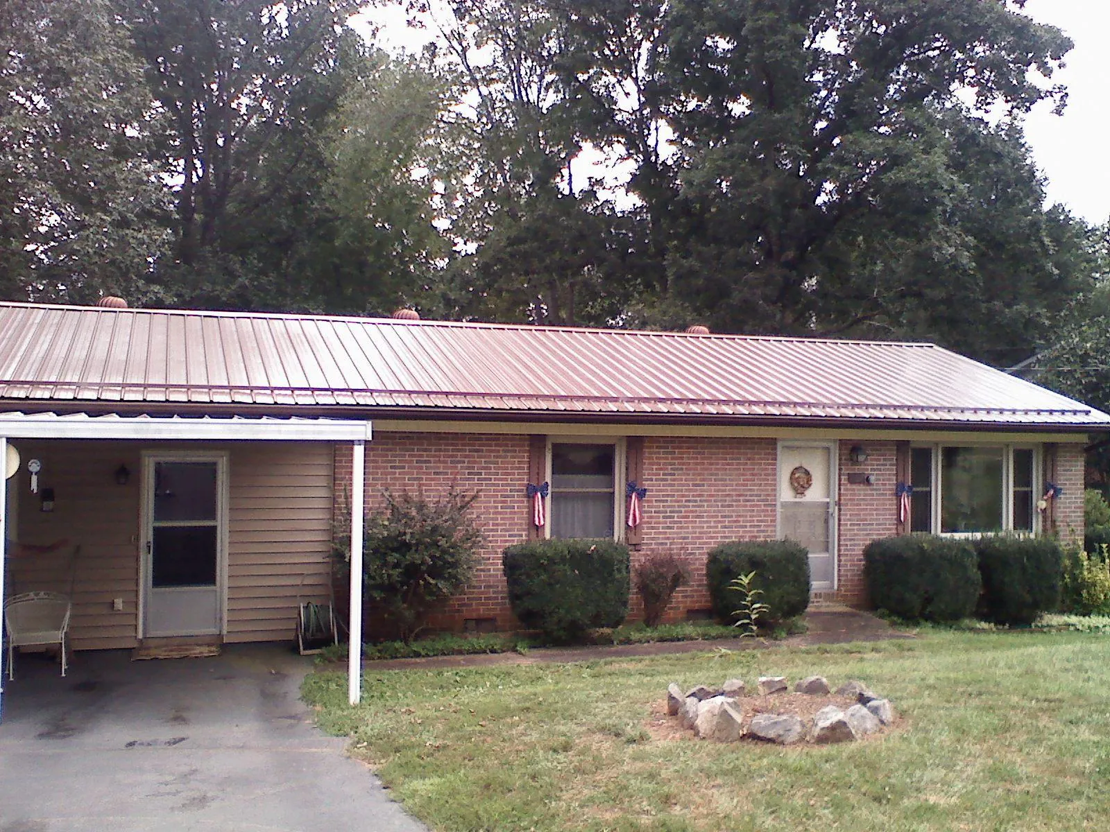 Bronze metal roof and carport on a brick ranch home — Roof Repair work by our crew in Green