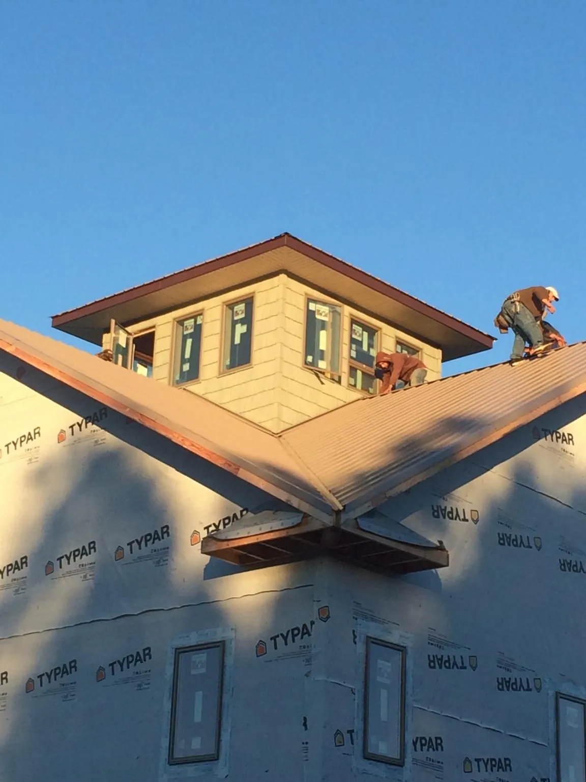 Roofers working around a rooftop cupola on a new metal roof at sunset — Roof Waterproofing in Green by Roofing Brothers